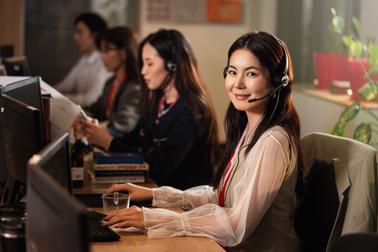 Kobieta w słuchawkach pracuje przy komputerze w biurze call center.