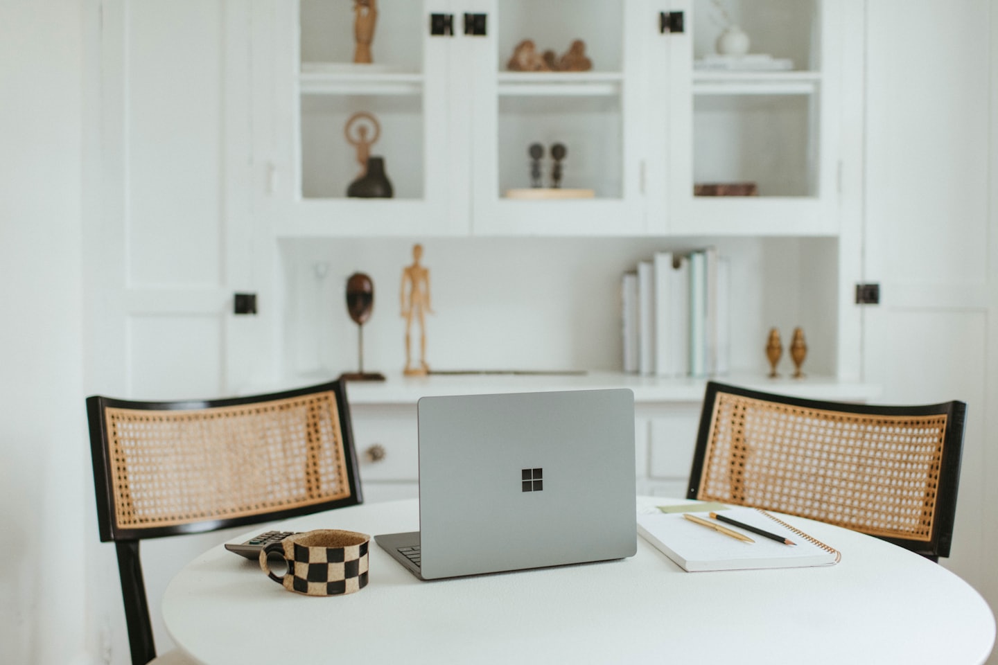 Laptop i materiały biurowe na okrągłym stole między krzesłami.